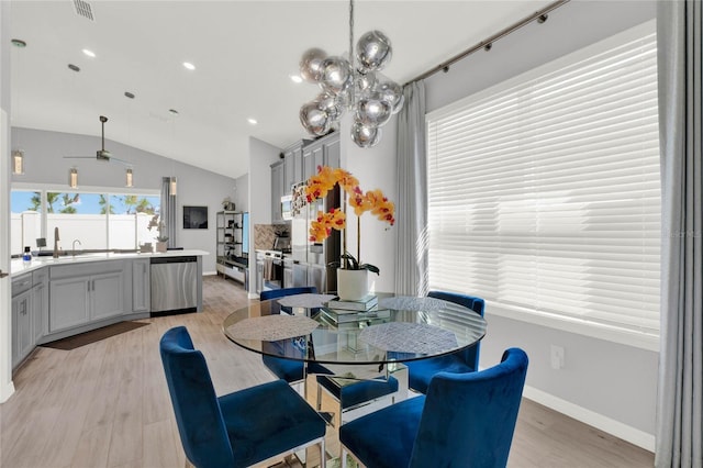 dining area with lofted ceiling, a chandelier, and light hardwood / wood-style floors