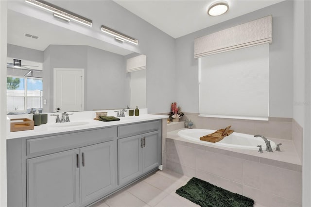 bathroom with tile patterned flooring, vanity, and tiled bath