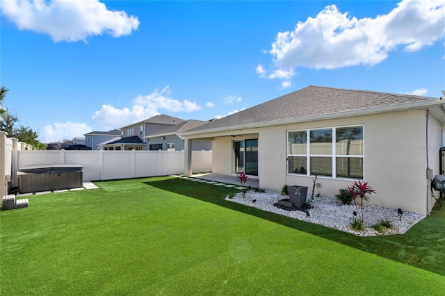 rear view of house featuring a hot tub, a patio, a yard, and ceiling fan