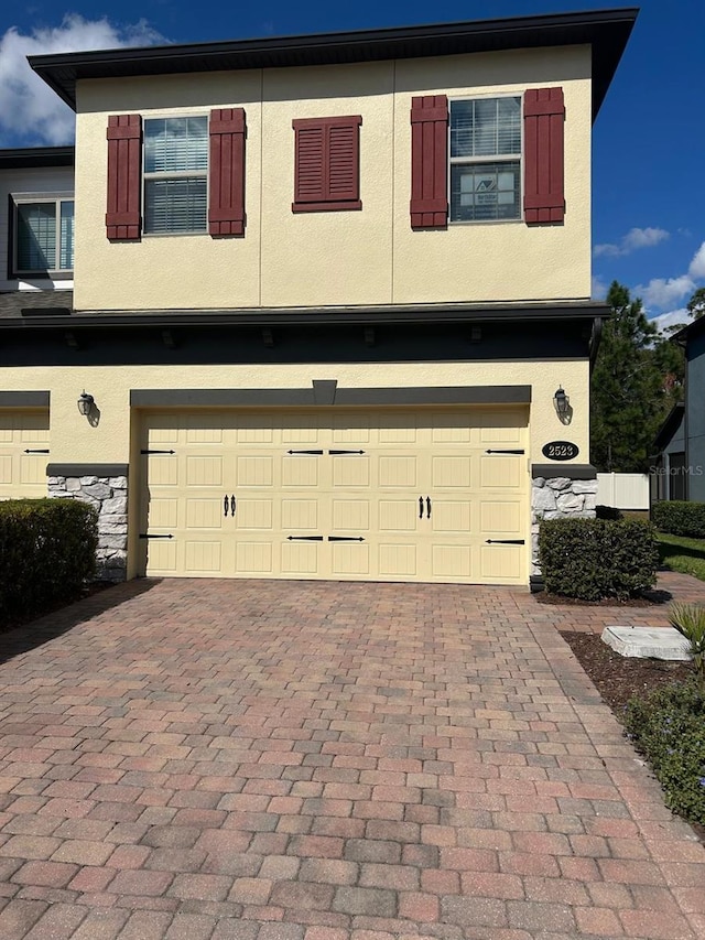 multi unit property with stucco siding, stone siding, and decorative driveway