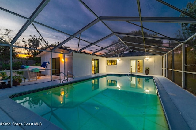 pool at dusk featuring a patio and glass enclosure