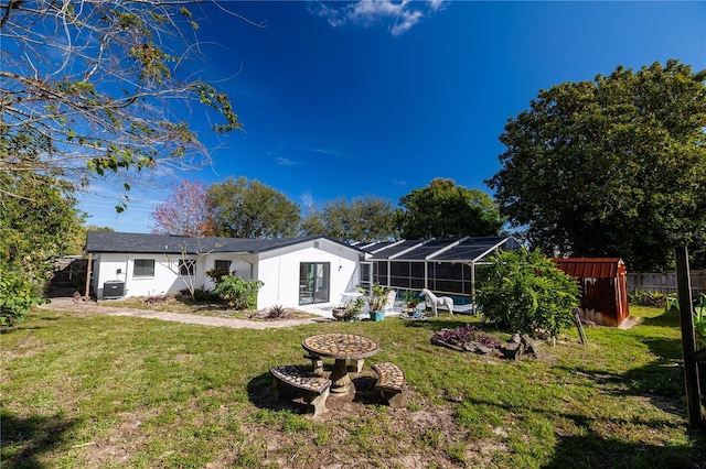 rear view of house with a lanai, a yard, and central AC