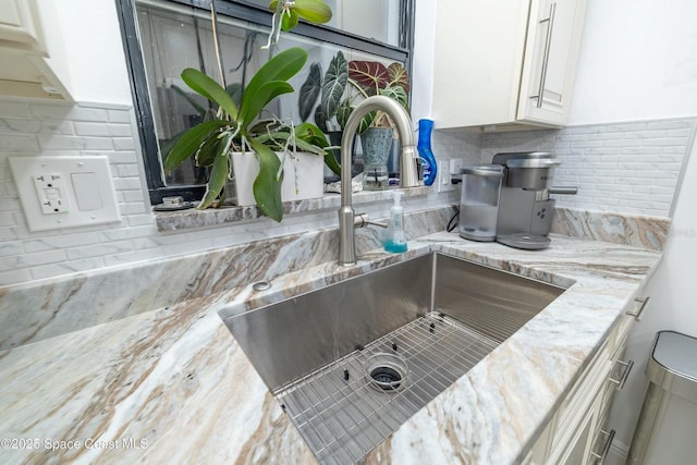 details featuring white cabinetry, light stone countertops, sink, and decorative backsplash