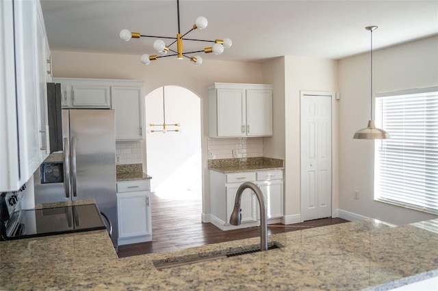 kitchen with sink, tasteful backsplash, range, hanging light fixtures, and white cabinets