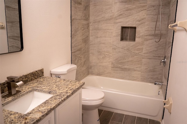 full bathroom with tiled shower / bath combo, vanity, hardwood / wood-style floors, and toilet