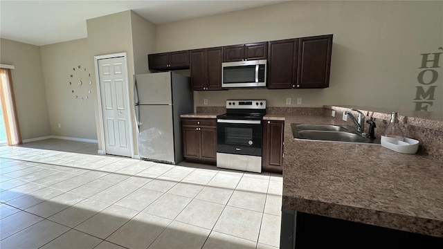 kitchen featuring sink, dark brown cabinets, stainless steel appliances, and light tile patterned flooring