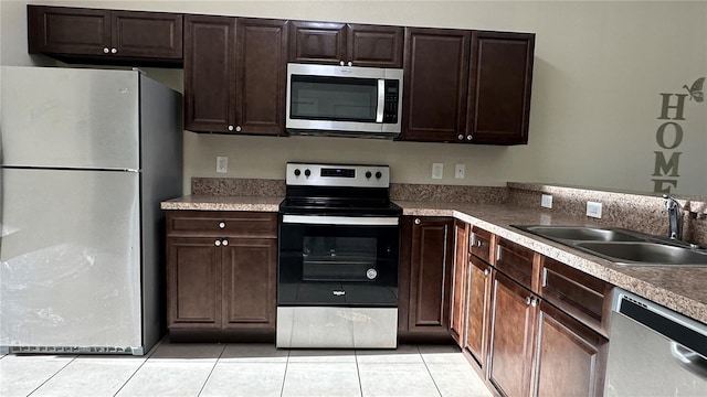 kitchen featuring dark brown cabinetry, sink, light tile patterned flooring, and appliances with stainless steel finishes