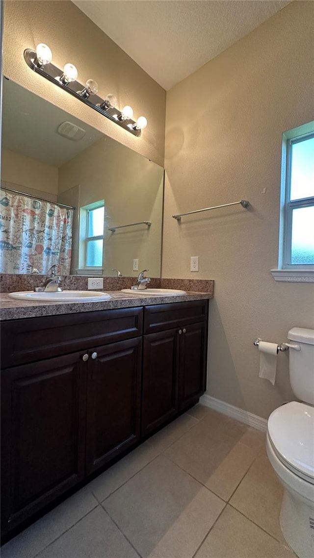 bathroom with tile patterned flooring, vanity, a textured ceiling, and toilet