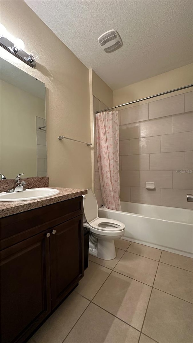 full bathroom featuring shower / tub combo with curtain, vanity, toilet, tile patterned floors, and a textured ceiling