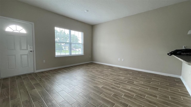 foyer entrance with dark hardwood / wood-style floors and a textured ceiling