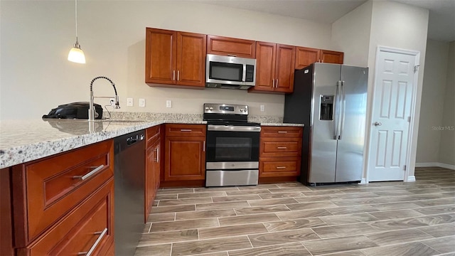 kitchen featuring light stone countertops, appliances with stainless steel finishes, sink, and decorative light fixtures