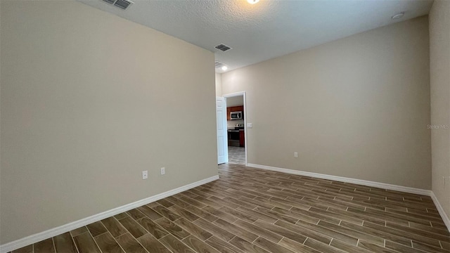 empty room featuring dark hardwood / wood-style flooring and a textured ceiling