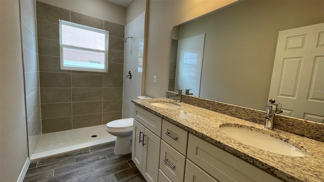 bathroom featuring vanity, a tile shower, and toilet