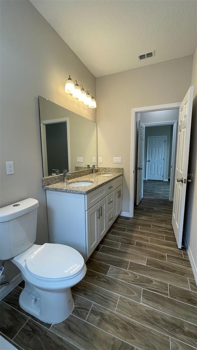 bathroom with vanity, a textured ceiling, and toilet