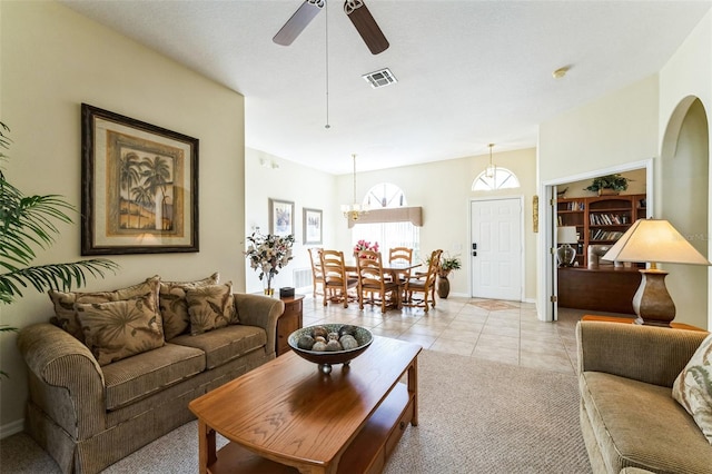 living area featuring arched walkways, light tile patterned floors, visible vents, a ceiling fan, and baseboards