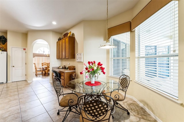 dining space with light tile patterned floors, baseboards, arched walkways, and recessed lighting