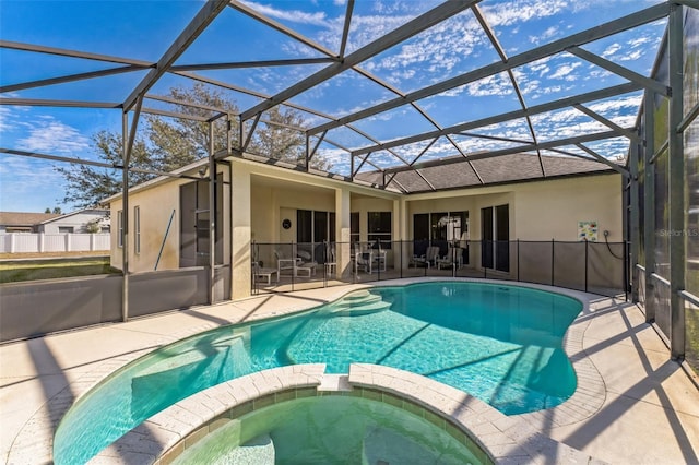 view of pool with an in ground hot tub, glass enclosure, and a patio