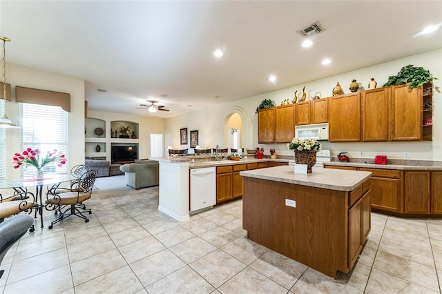 kitchen featuring white appliances, brown cabinetry, light countertops, and open floor plan