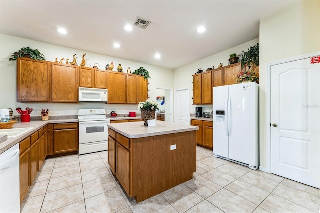 kitchen featuring sink, light tile patterned floors, white appliances, and a center island