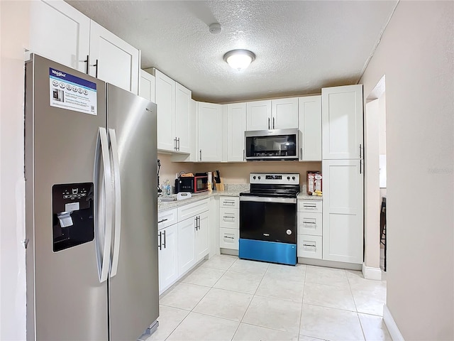 kitchen with a textured ceiling, light tile patterned flooring, white cabinets, and appliances with stainless steel finishes