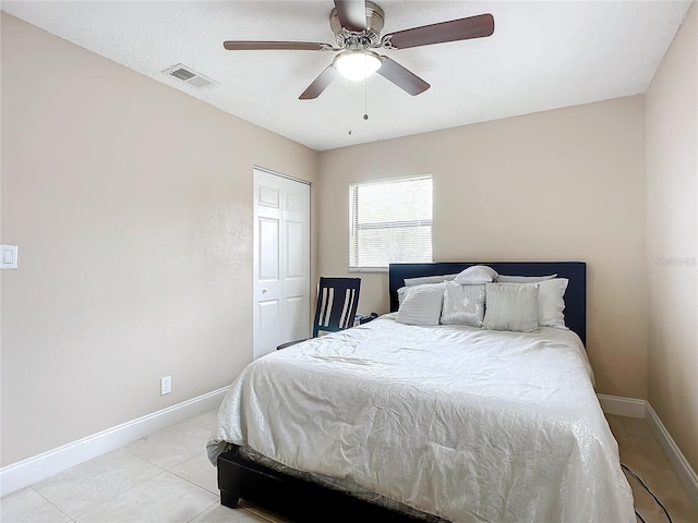 bedroom featuring light tile patterned floors, ceiling fan, and a closet