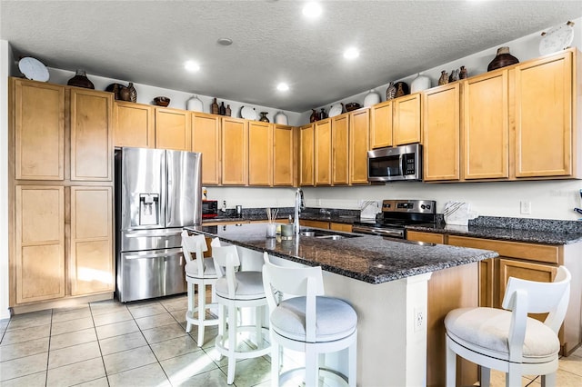 kitchen featuring appliances with stainless steel finishes, sink, a kitchen breakfast bar, a kitchen island with sink, and light tile patterned floors