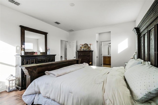 bedroom with ensuite bathroom and light wood-type flooring