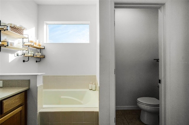 bathroom with a relaxing tiled tub, vanity, toilet, and tile patterned flooring