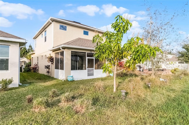 back of house featuring a sunroom and a lawn