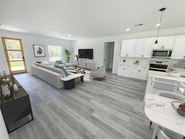 living area featuring recessed lighting, visible vents, and light wood-style flooring