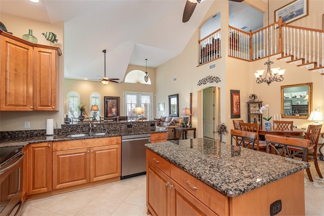 kitchen with a kitchen island, appliances with stainless steel finishes, dark stone counters, and decorative light fixtures