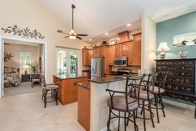 kitchen featuring a center island, dark stone countertops, a kitchen breakfast bar, kitchen peninsula, and stainless steel appliances