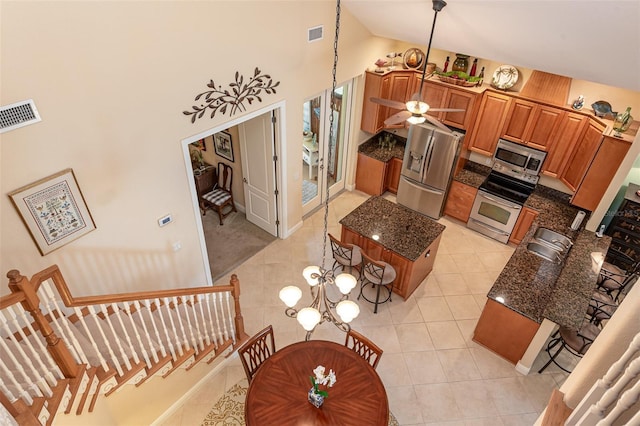 kitchen featuring light tile patterned flooring, a kitchen island, appliances with stainless steel finishes, high vaulted ceiling, and sink