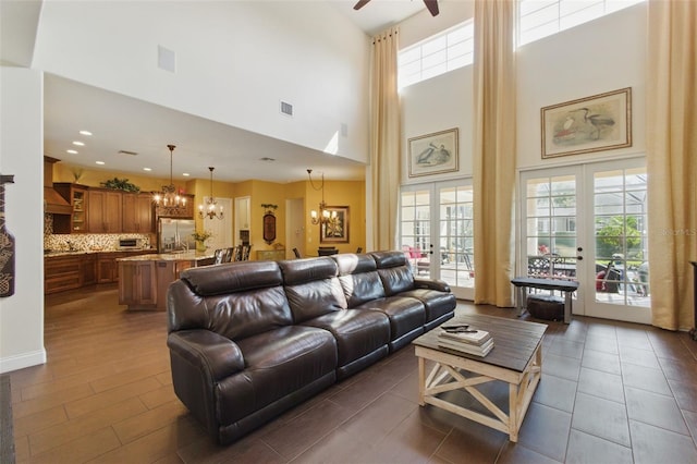 living room featuring ceiling fan with notable chandelier and french doors