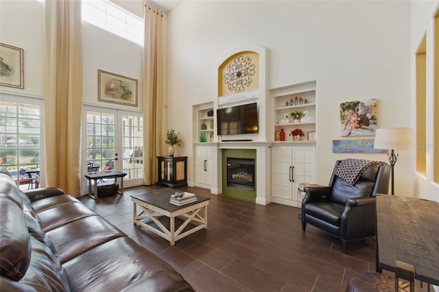 living room with a high ceiling, built in shelves, and french doors