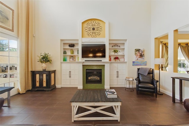 sitting room featuring built in shelves, plenty of natural light, and a high ceiling