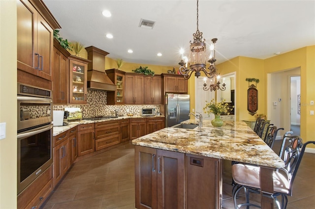 kitchen featuring premium range hood, a breakfast bar area, decorative light fixtures, a chandelier, and appliances with stainless steel finishes