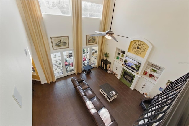 living room with french doors, a healthy amount of sunlight, dark hardwood / wood-style flooring, and a towering ceiling