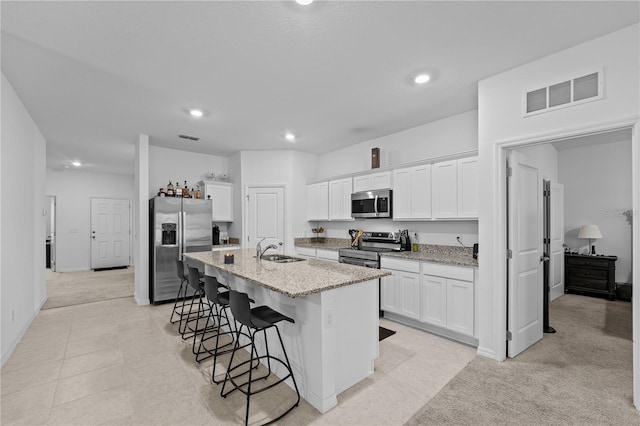 kitchen with stainless steel appliances, sink, a kitchen island with sink, and white cabinets