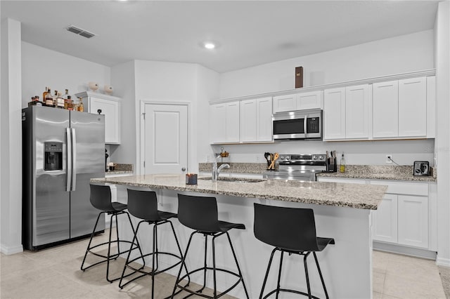 kitchen with white cabinetry, appliances with stainless steel finishes, sink, and a center island with sink