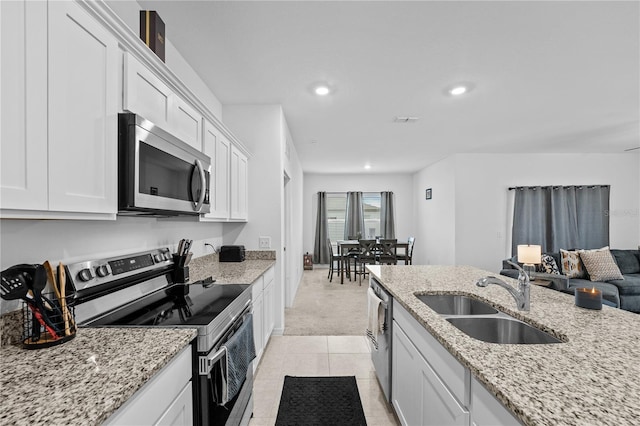 kitchen with stainless steel appliances, white cabinetry, light stone countertops, and sink