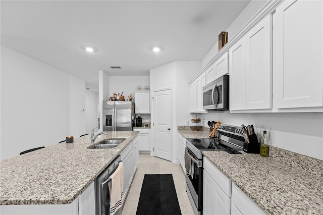 kitchen featuring sink, white cabinetry, a center island with sink, stainless steel appliances, and light stone countertops