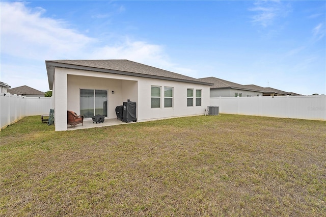 rear view of property with a yard, a patio, and central air condition unit