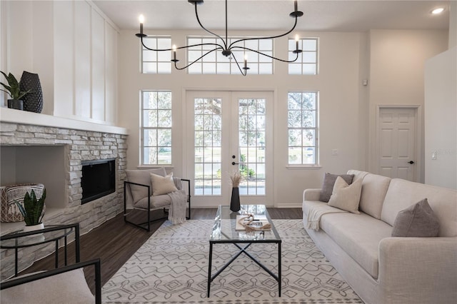 living room with light hardwood / wood-style flooring, french doors, a chandelier, and a high ceiling