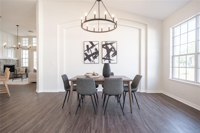 dining space with an inviting chandelier, a fireplace, dark hardwood / wood-style flooring, and a wealth of natural light