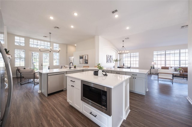 kitchen with a kitchen island, appliances with stainless steel finishes, decorative light fixtures, and kitchen peninsula