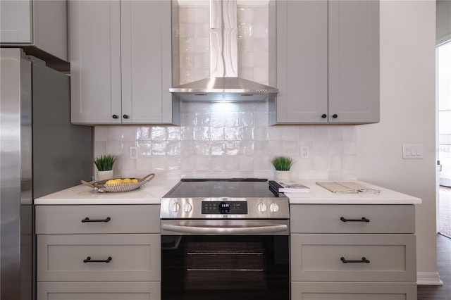 kitchen with backsplash, gray cabinetry, appliances with stainless steel finishes, and wall chimney range hood