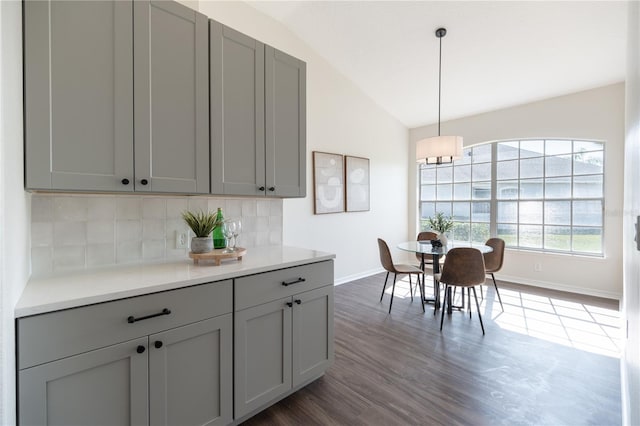 kitchen with vaulted ceiling, gray cabinetry, and decorative light fixtures