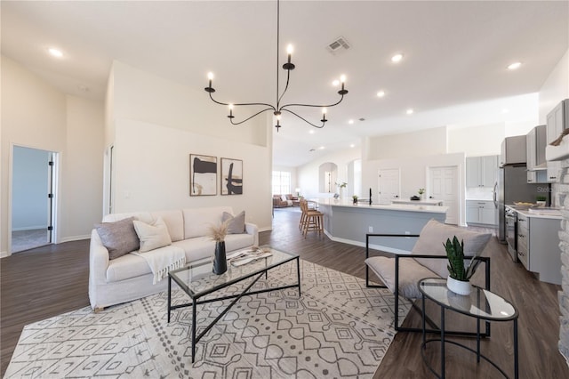 living room featuring high vaulted ceiling, sink, a notable chandelier, and light hardwood / wood-style floors