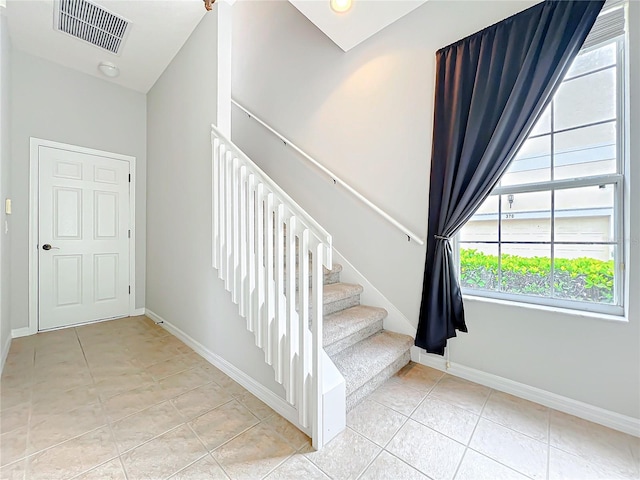 stairway featuring tile patterned floors, baseboards, and visible vents